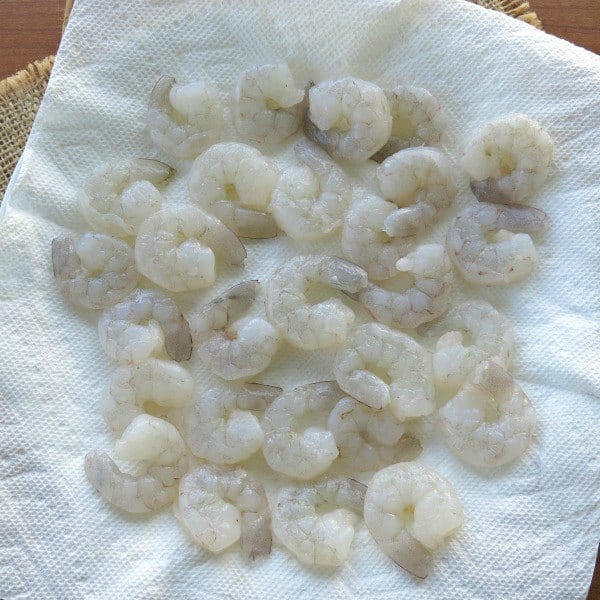 Raw shrimp that is peeled, deveined and has the tail removed on a paper towel.