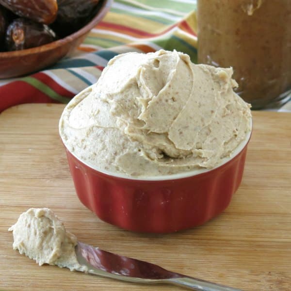 Date Paste Cream Cheese Frosting in a small bowl with knife in front with frosting on it.