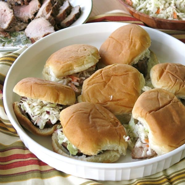 Pork Tenderloin sliders topped with coleslaw on a serving platter.