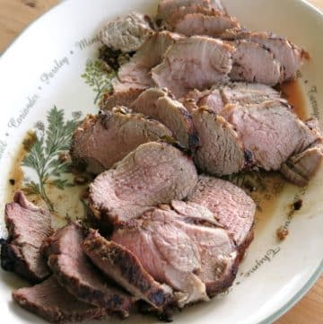Sliced pork tenderloin in red wine marinade on a platter