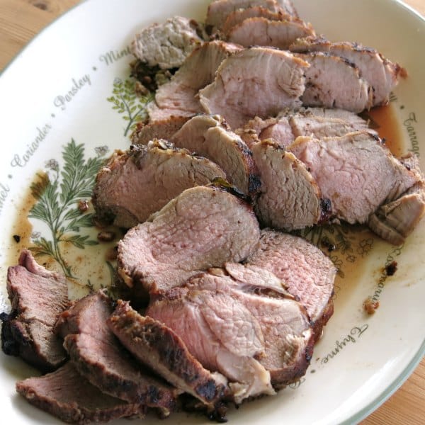 Sliced pork tenderloin in red wine marinade on a platter.