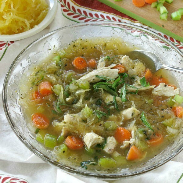Soup with chicken added in bowl with spoon on napkin