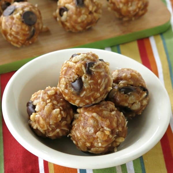 No-bake date balls with rice krispies in a bowl with more on a cutting board in the background.