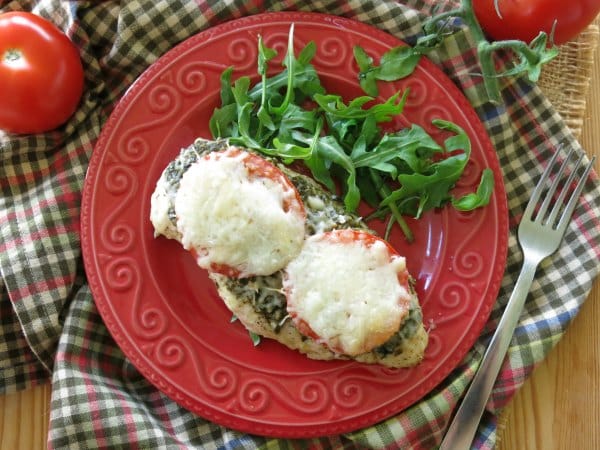 Baked Pesto Chicken on a plate with arugula next to it.