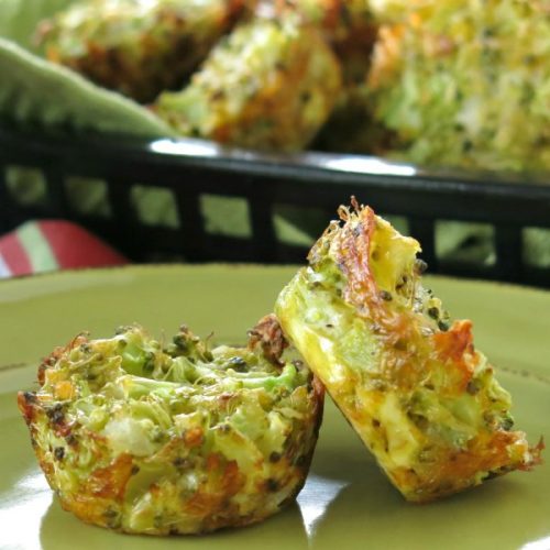 Two broccoli muffins on plate with a basket of muffins behind them.