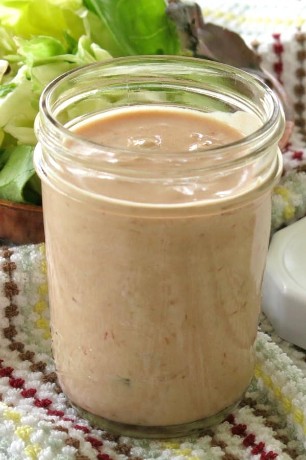 Creamy Salsa Dressing in a small Mason jar with lettuce in bowl behind it