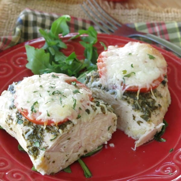 Healthy Pesto Chicken on plate cut into two pieces with fork in background.