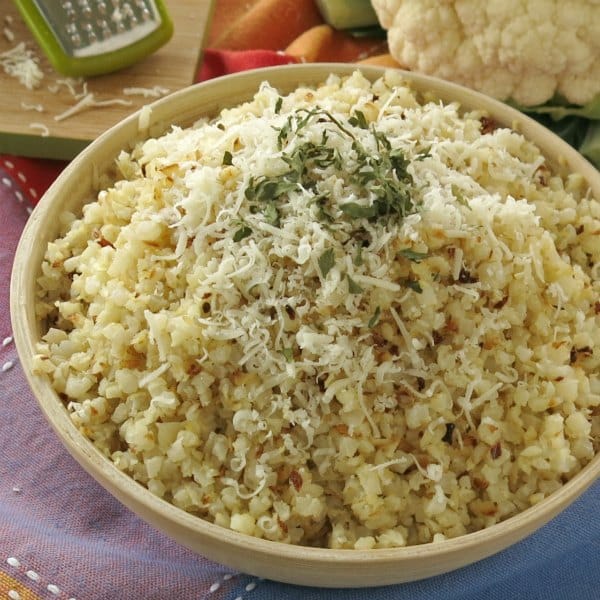 Bowl full of roasted cauliflower rice topped with parmesan cheese and parsley