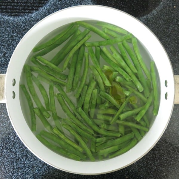 Fresh green beans in a pot of water on the stove.