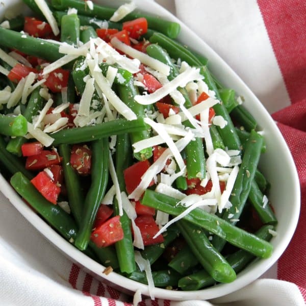 Easy green beans and tomatoes topped with Parmesan Cheese in a serving dish.