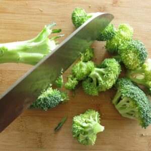 Broccoli florets being cut from stalks.