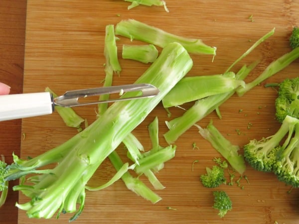 vegetable peeler removing outer layer of broccoli stalk