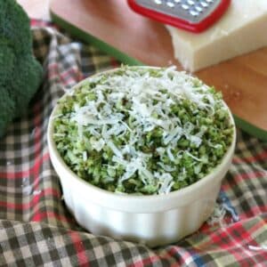 Roasted broccoli rice topped with Parmesan cheese in a bowl with broccoli and cheese in the background