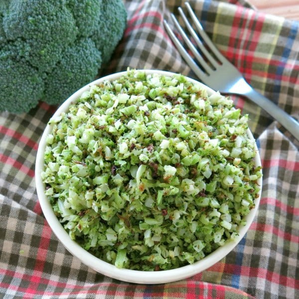 Roasted broccoli rice in a bowl next to a head of broccoli and a fork