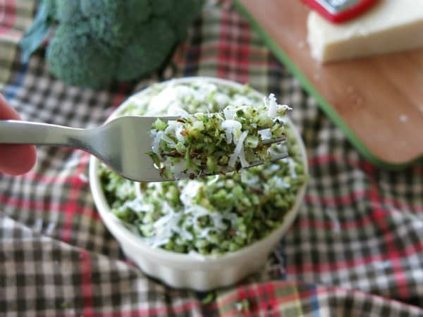 Fork holding roasted rice broccoli with Parmesan cheese and garlic