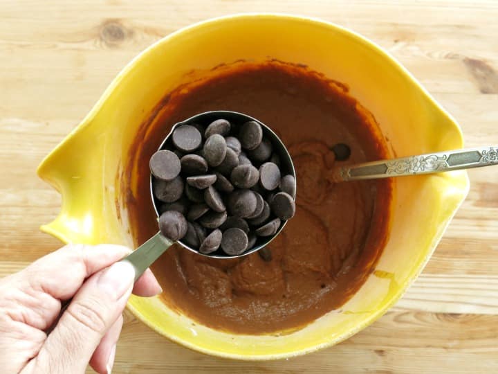 Dark Chocolate Chips in measuring cup over chocolate pumpkin batter.