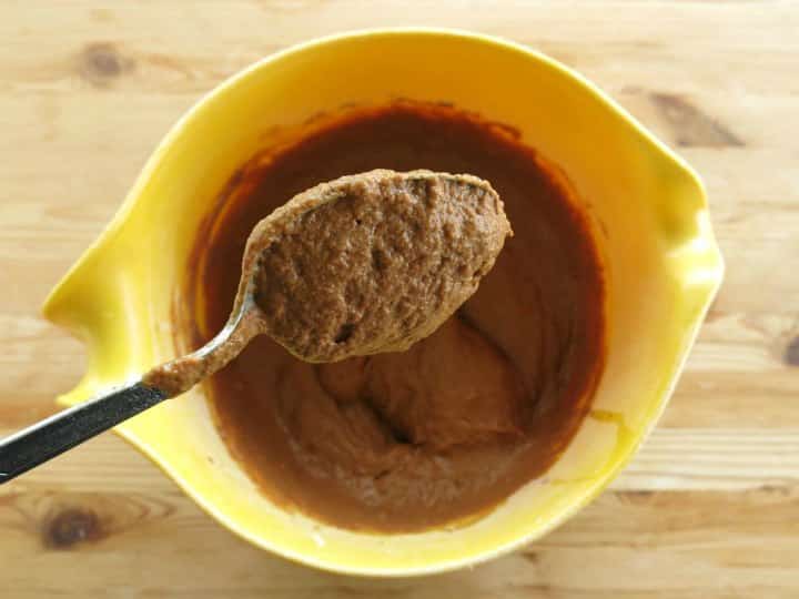 Healthy Chocolate Pumpkin Muffin batter on a spoon over a mixing bowl.