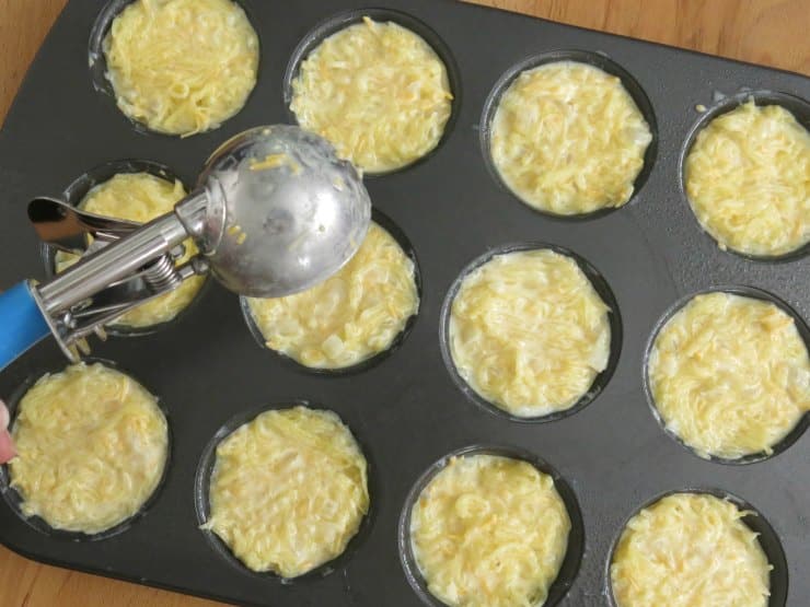 Scoop portioning spaghetti squash au gratin mixture into muffin pan.