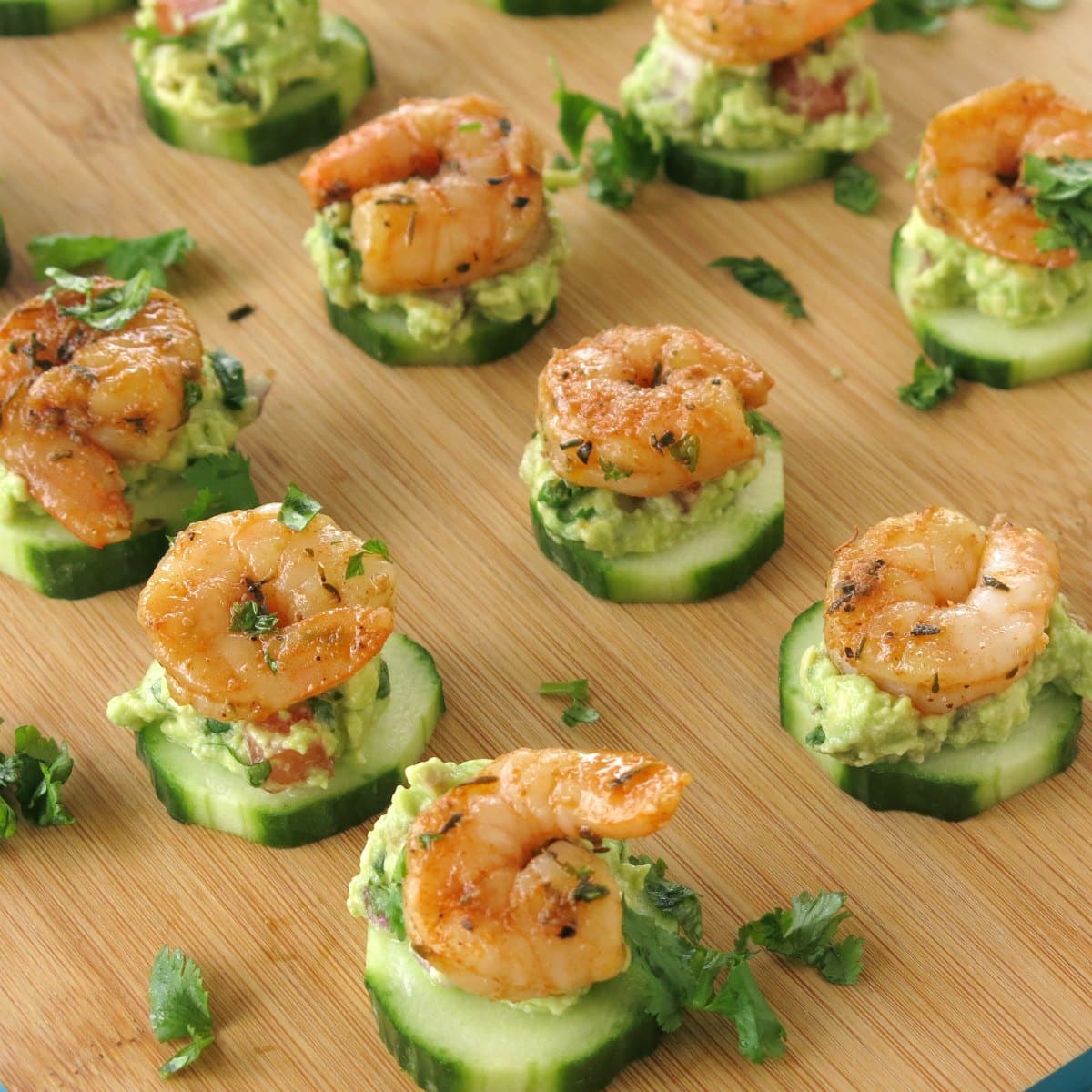 Cajun Shrimp Guacamole Bites on Cucumber rounds on serving board.