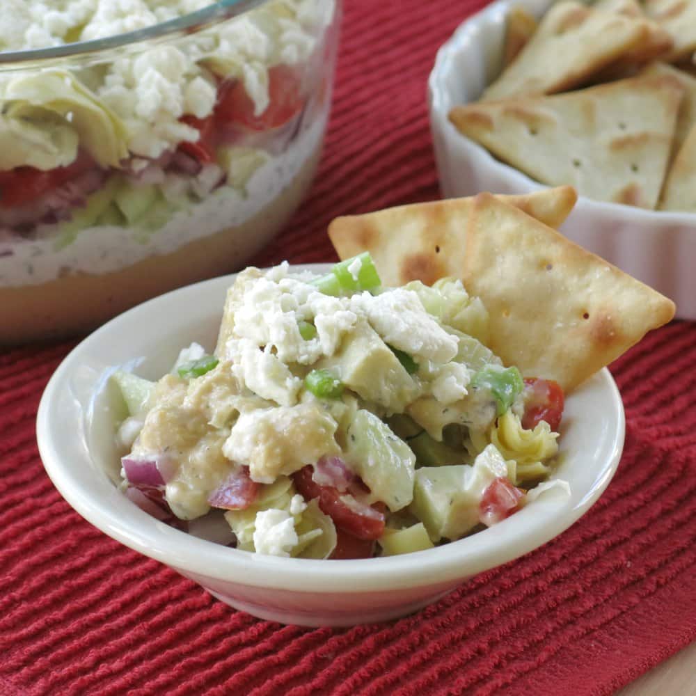 Serving of Greek dip in a small bowl with two crackers on the side.