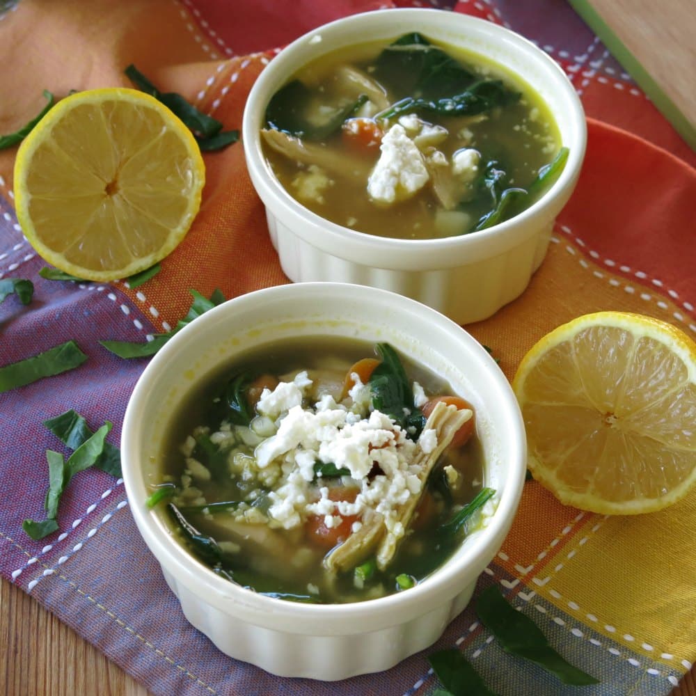 Two bowls of lemon chicken soup with cauliflower and feta cheese.