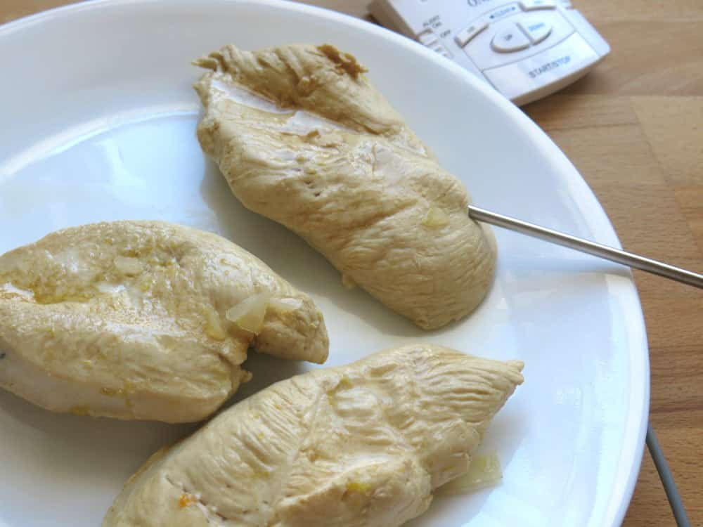 3 poached chicken breast on plate with temperature probe inserted.