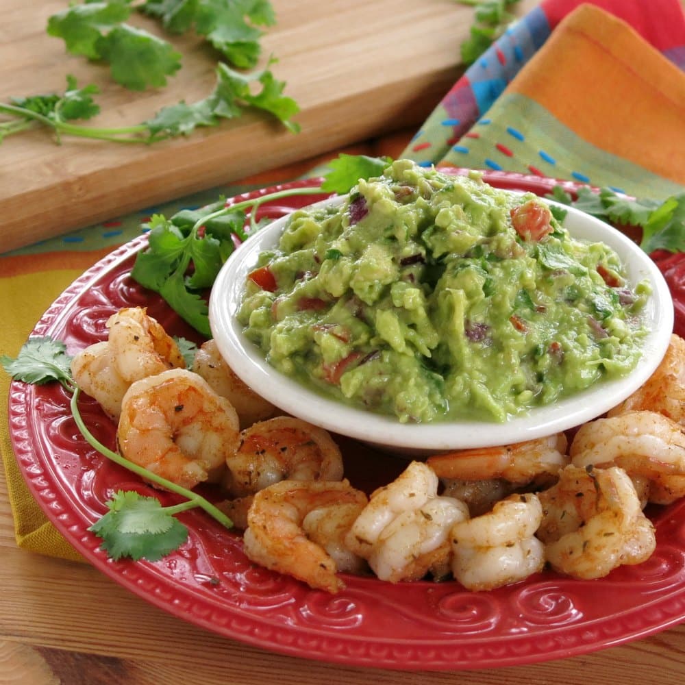 Guacamole surrounded by blackened shrimp.