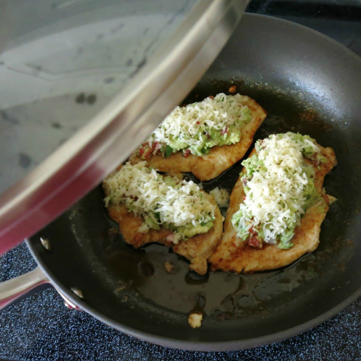 Chicken guacamole in pan before cheese has melted with lid being placed on top