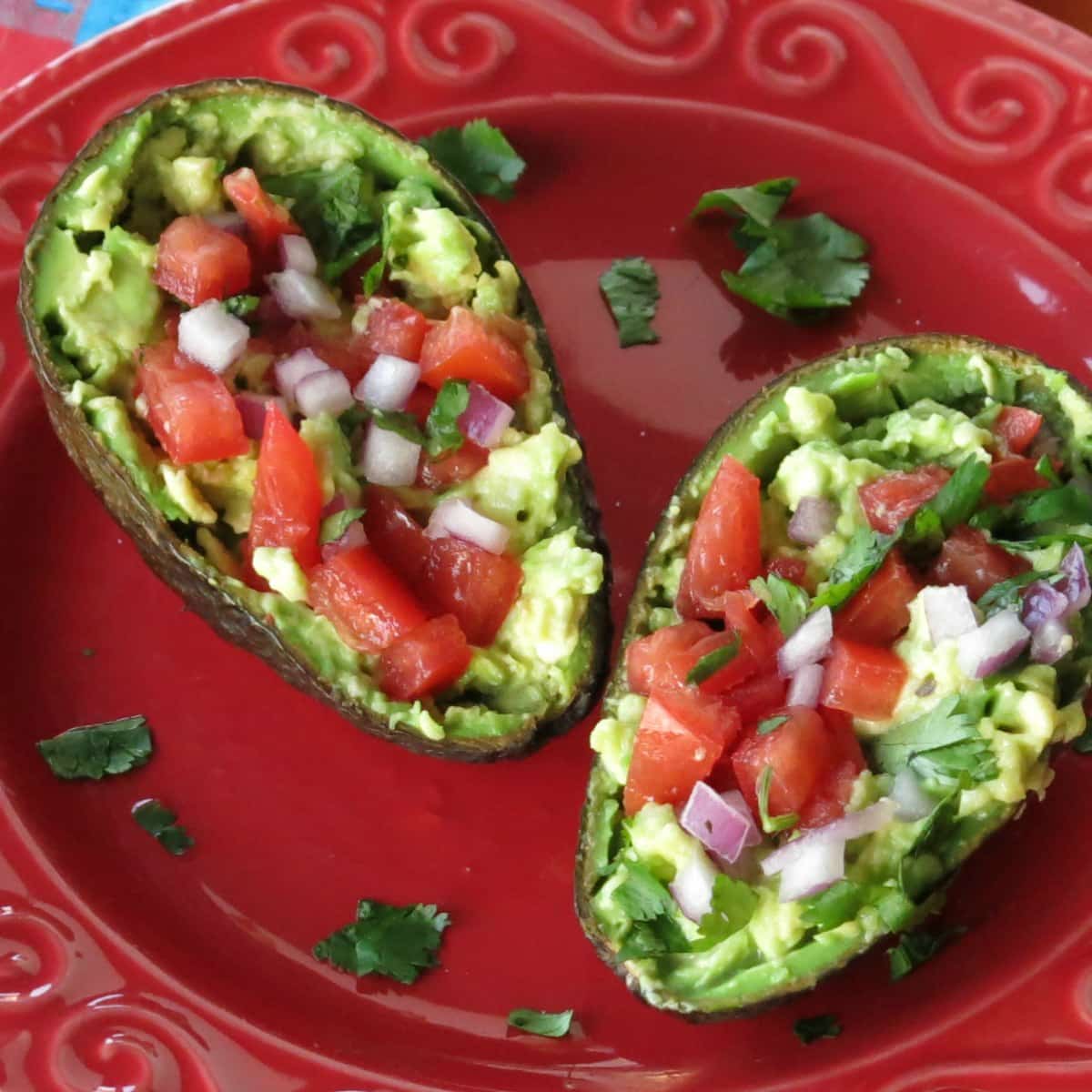 An avocado cut in half with guacamole inside each half.