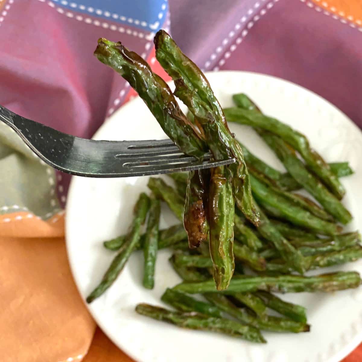 Fork with 3 green beans cooked in an air fryer