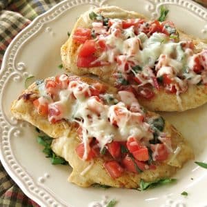 Two bruschetta chicken breasts on a plate.