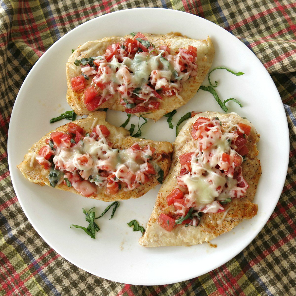 Cooked and finished bruschetta chicken on white plate.