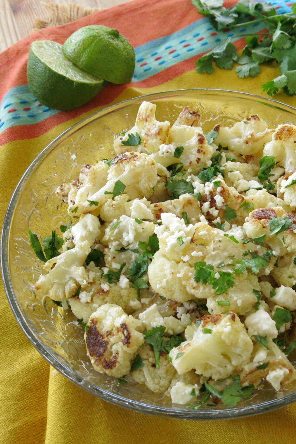 Elote cauliflower on plate with limes and cilantro in background