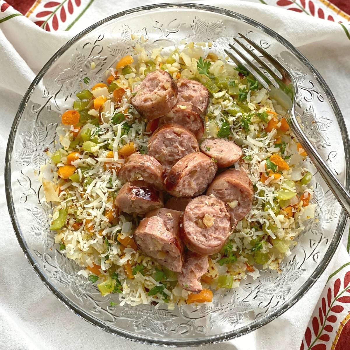 Cauliflower Rice Pilaf topped with sausage in a bowl.