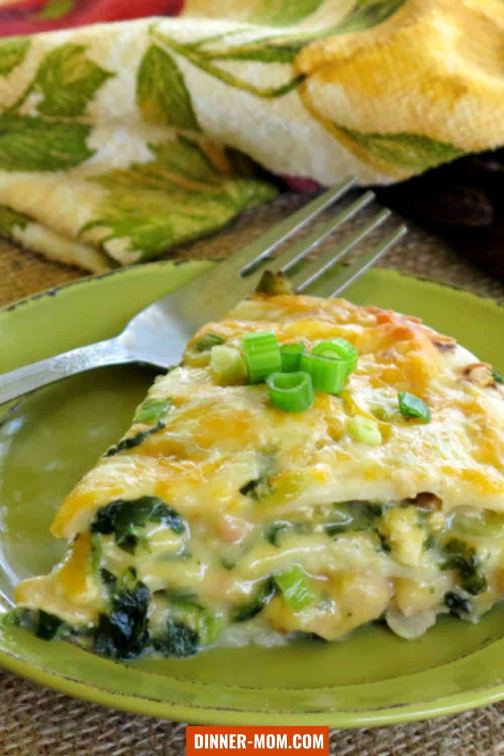 Slice of layered chicken enchilada casserole on a dish with a fork.