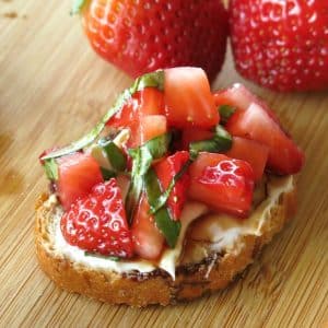 Strawberry Bruschetta with cream cheese, basil and balsamic vinegar reduction on thin slice of baguette.