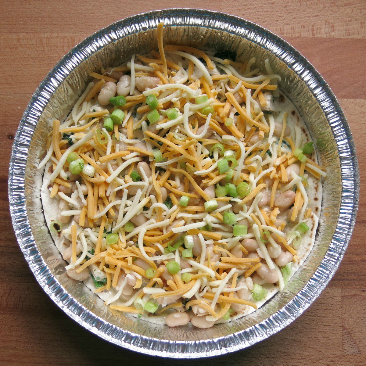 First layer of chicken enchilada pie in a round cake pan.