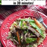 Sesame beef stir fry with carrots, snow peas, green onions, and sesame seeds served over cauliflower rice on a red plate.
