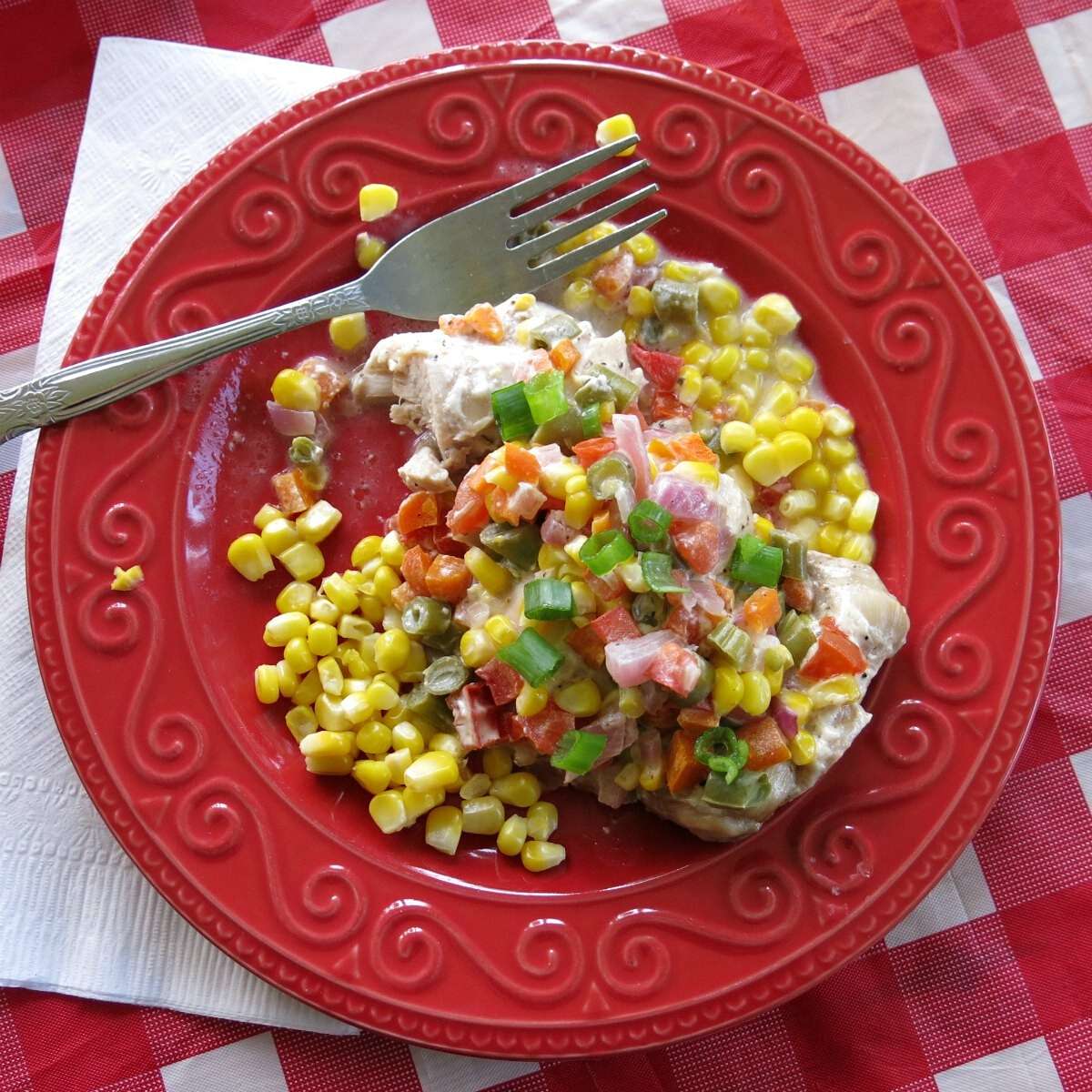 Ranch chicken topped with vegetables on a plate with a fork. 