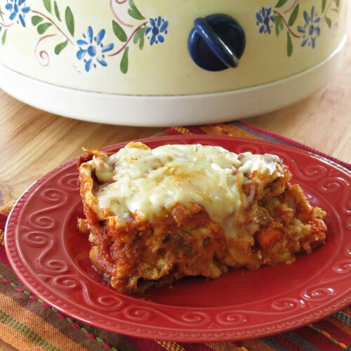 Slice of crock-pot vegetable lasagna on a plate in front of a slow cooker.