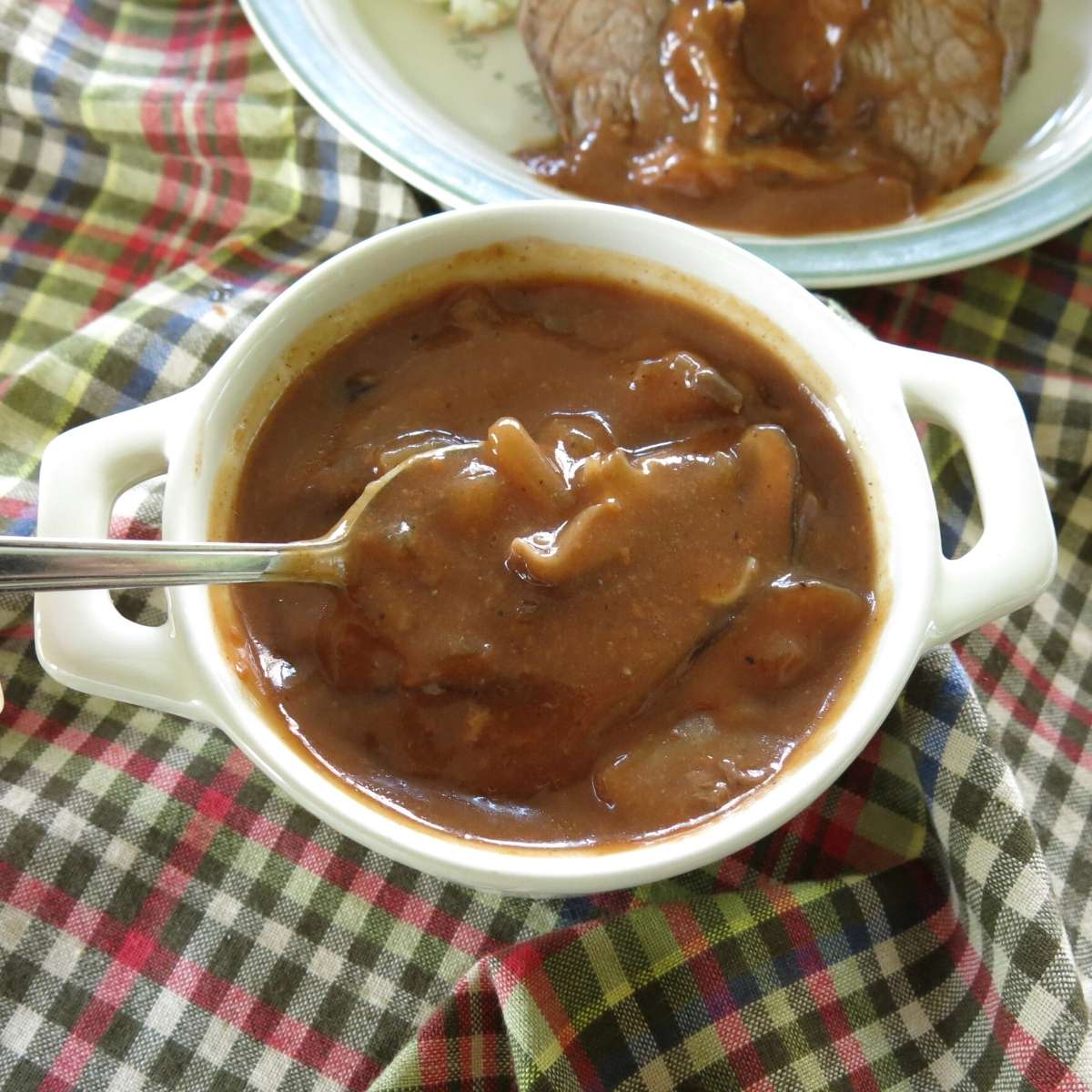 Spoonful of red wine mushroom gravy being lifted out of serving bowl.