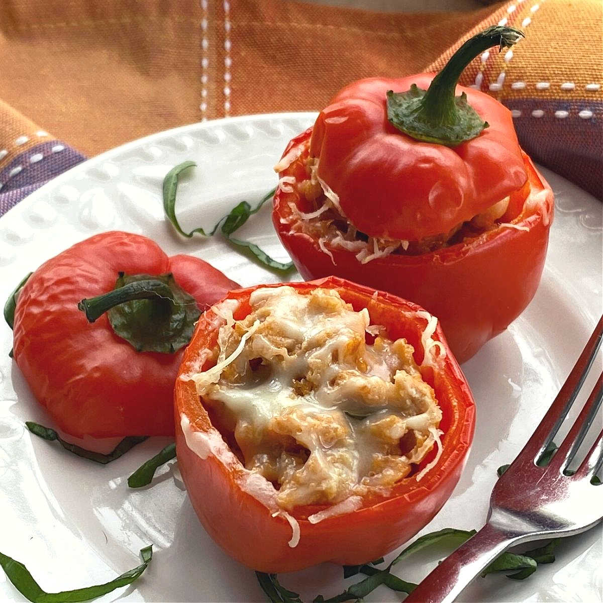 2 cooked chicken meatloaf stuffed peppers on a plate with a fork. 