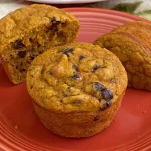 2 healthy Greek yogurt pumpkin muffins on plate with one cut in half.