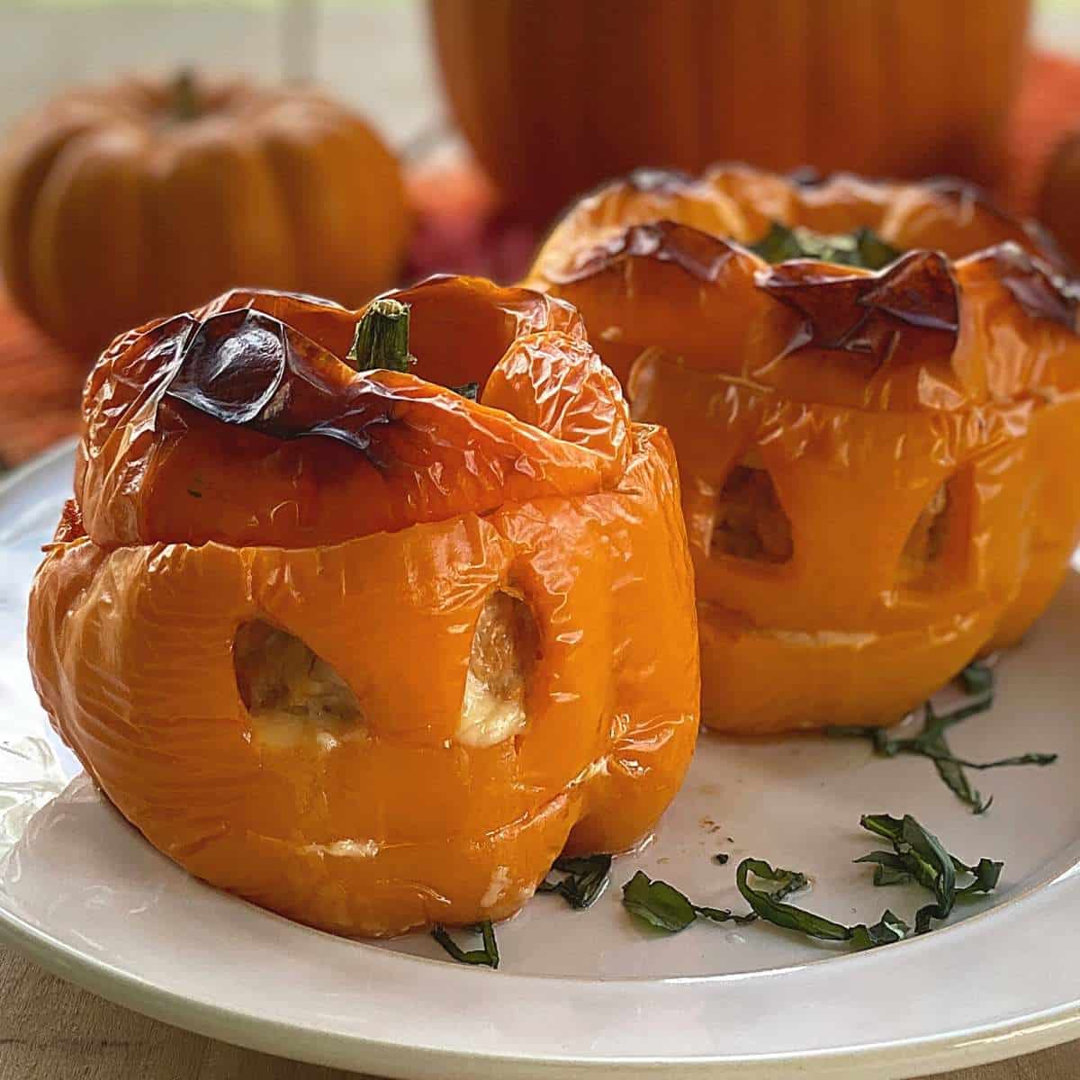 2 cooked orange bell peppers with a jack-o-latern face cut into them. 