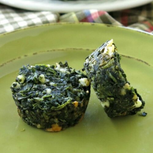 2 spinach egg muffins with feta cheese on a green plate.