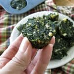 Hand holding up a spinach feta egg bite over a pan with more in it.