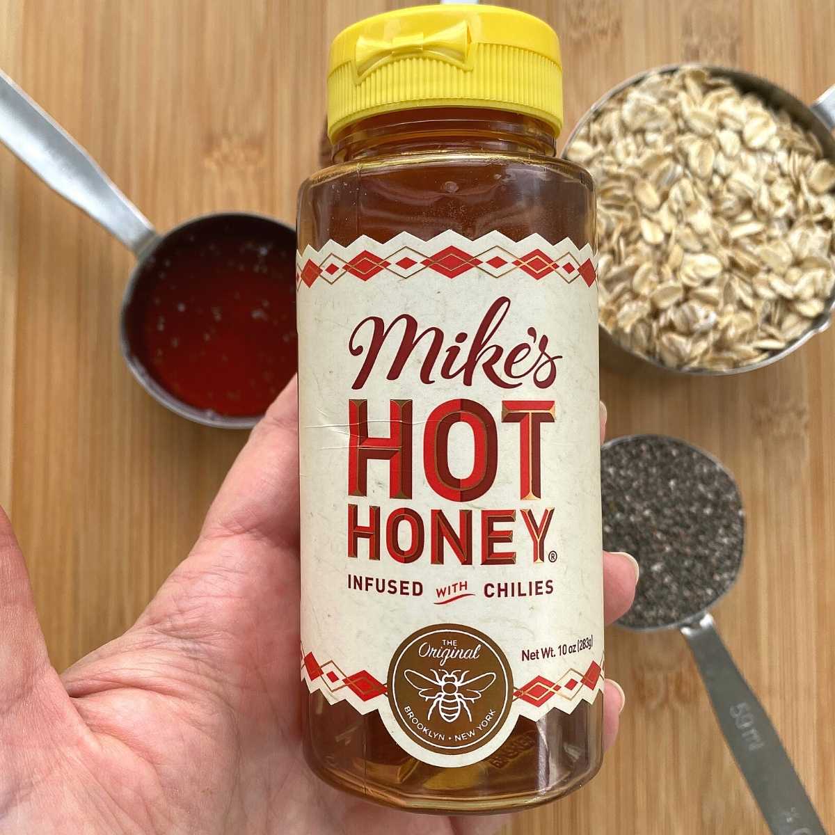 Hand holding a bottle of Mike's Hot Honey.