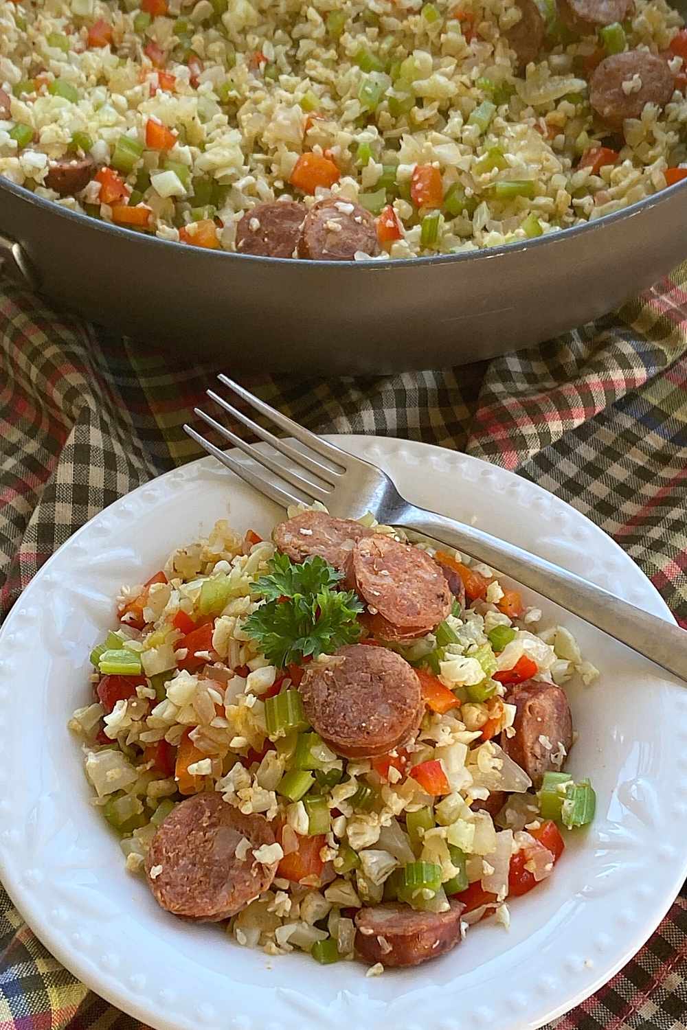 Bowl with a single serving of Cajun cauli-rice with skillet in the background.