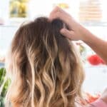 Person scratching that back of head looking into an organized refrigerator with the doors open.