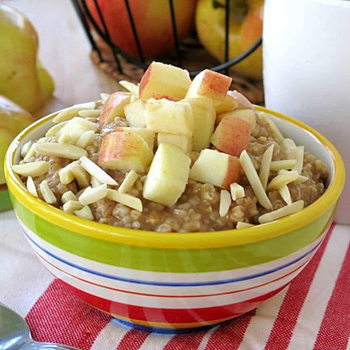 Bowl of slow cooker steel cut oatmeal in a bowl topped with apples and almonds.